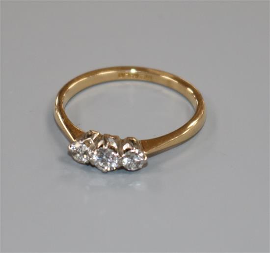 An 18ct gold and platinum, three stone diamond ring, size M.